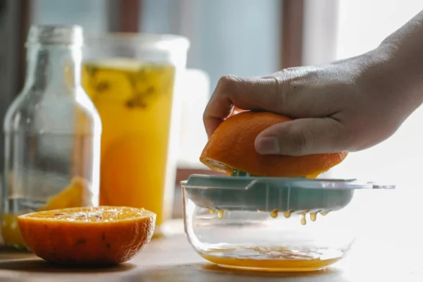 Copo de suco de laranja fresco com laranjas ao lado, ilustrando os benefícios do suco de laranja para a saúde.