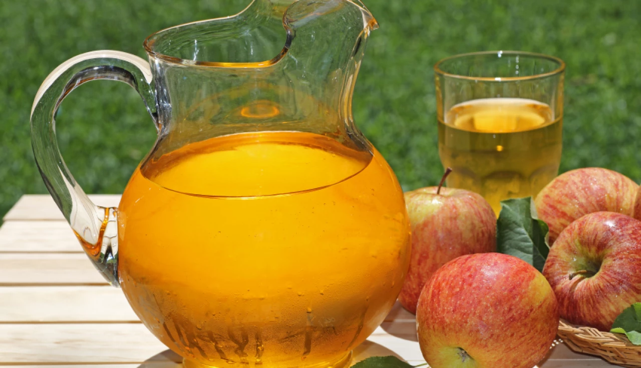 uma jarra de vidro com suco ao lado de maçãs uma jarra de vidro com suco ao lado de maçãs